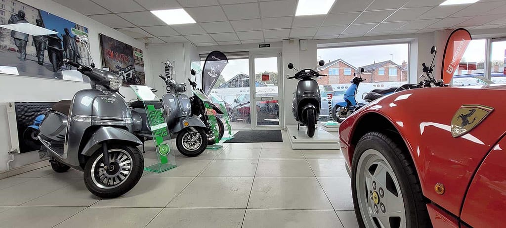 Ferrari and electric scooters inside Checkpoint Specialist Cars showroom