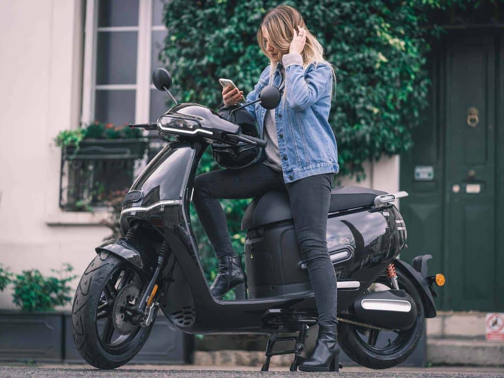 Blonde woman on a mobile phone sitting on black electric moped