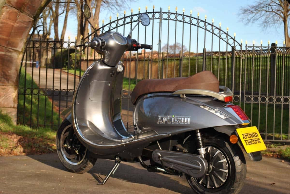 Electric road legal grey scooter in front of large gates