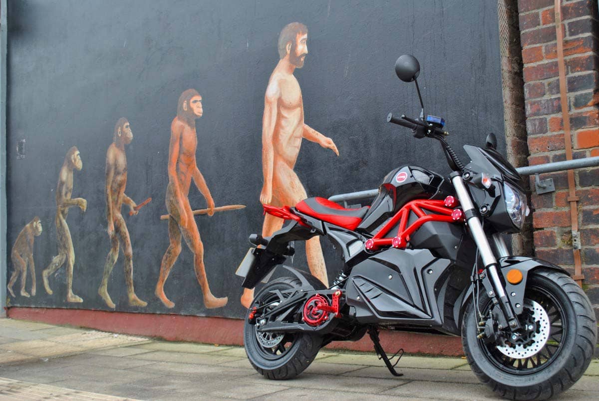 Red Ev0 in front of evolution of man painted on a wall