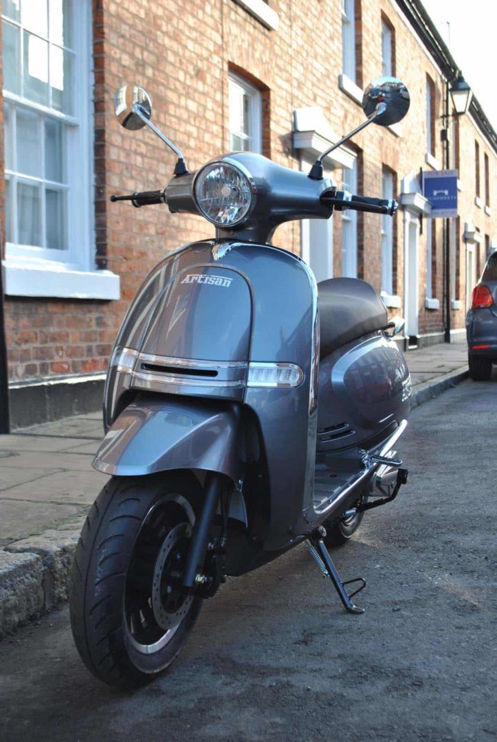 Grey electric scooter parked on road outside houses